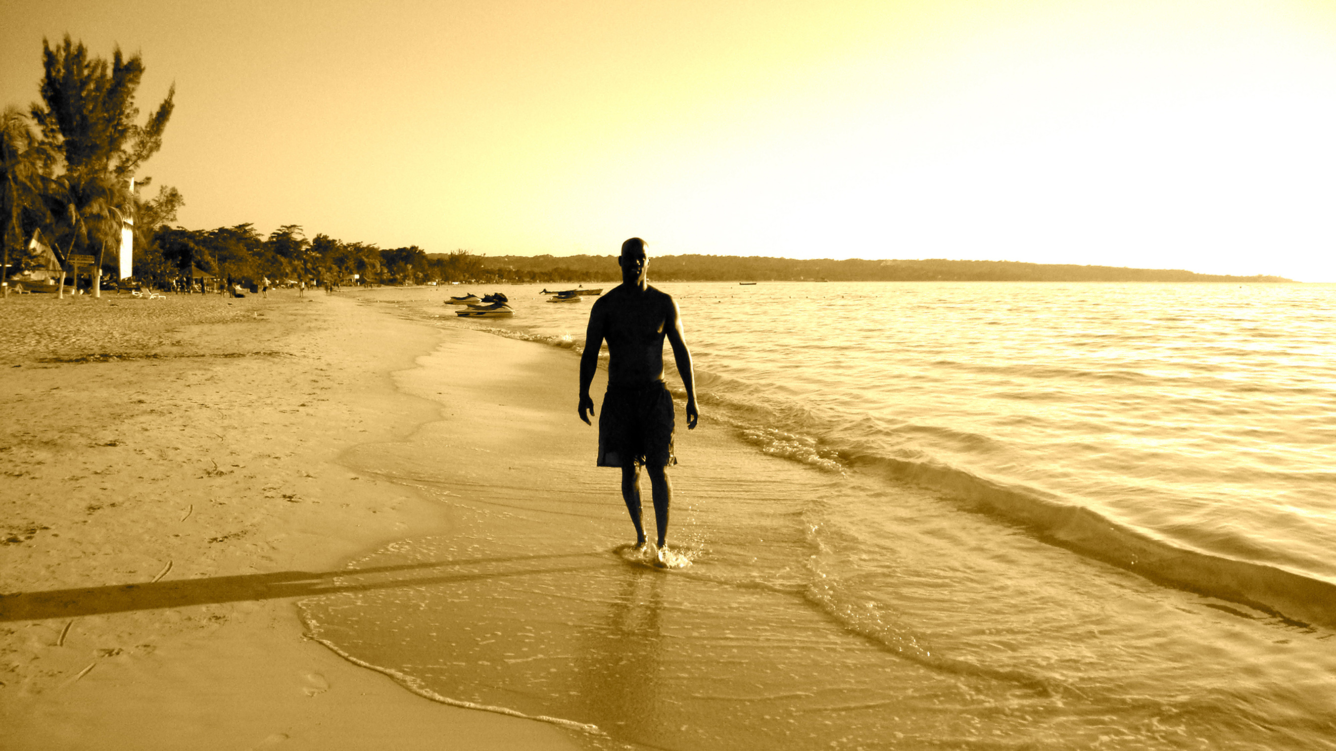 Man walking along beach sunset - Bak2Buks Media